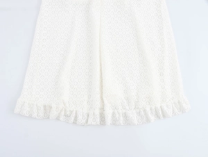 Detailed view of white knitted texture fabric with a ruffled hem on the dress