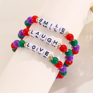 Detail of three colorful beaded bracelets with SMILE, LAUGH, and LOVE letter beads