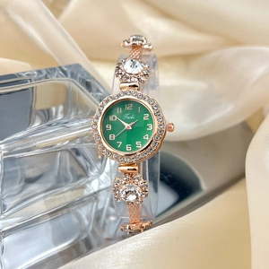 Detail of rose gold quartz watch with green dial and rhinestones on beige silk fabric