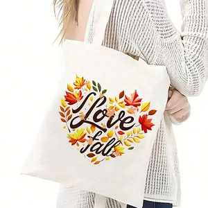 Detail of white canvas tote bag with Love Fall maple leaf heart graphic worn by a model