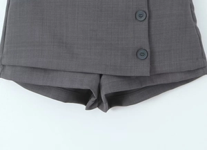Dettaglio ravvicinato della gonna-pantalone grigio scuro con bottoni e tessuto premium