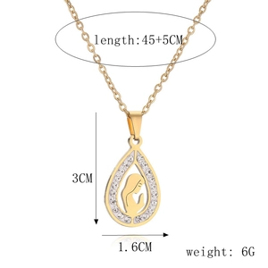 Detail of gold drop pendant necklace with praying silhouette and white zircon inlay