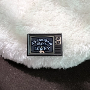 Retro TV enamel pin with 'Are You Afraid of the Dark?' text on white fur background