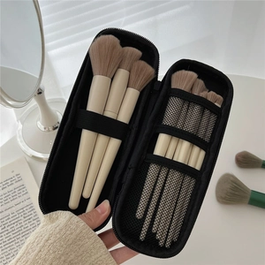 Close-up of portable makeup brush set in a black zippered travel pouch with mesh detail