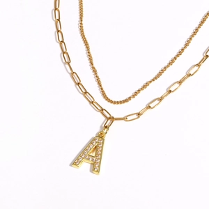 Close-up of gold double-layer necklace with a zircon-encrusted letter A pendant on white