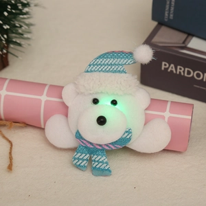 Detail of a glowing white bear Christmas brooch with a striped knit hat and LED lights
