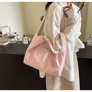 Rosafarbene Falten-Stofftasche mit KISS YOURSELF Label, getragen in einem Café-Ambiente