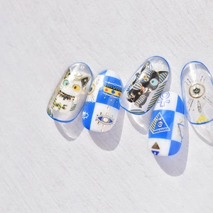 Detail of Egyptian cat and Horus eye gold foil nail stickers in blue and white colors