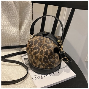 Detail of a brown leopard print barrel bucket bag with black leather trim on a chair