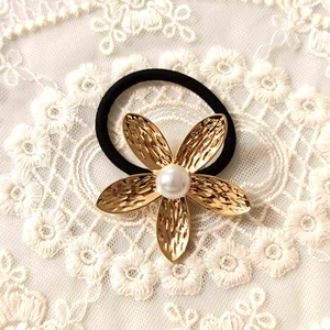 Detailed shot of golden flower hair tie with white pearl on white lace background