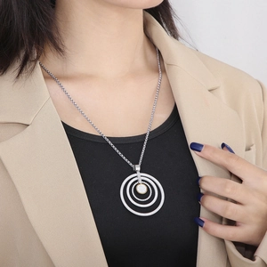 Model wearing a multi-layered two-tone pendant necklace with crystal pavé and steel chain