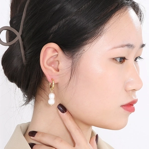Détail de boucles d'oreilles perles élégantes dorées portées par un mannequin