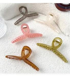 Close-up of five colorful translucent matte resin hair claws on white plush fabric
