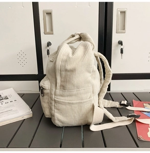Seitenansicht des weißen Cord-Rucksacks mit feinen Texturdetails auf einer Holzoberfläche