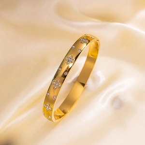 Elegant gold-plated stainless steel bangle with sparkling clover-shaped crystal studs