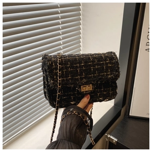 Close-up of black and gold tweed chain bag featuring a vintage metal turn-lock closure
