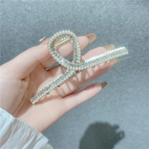 Détail d'une pince à cheveux élégante ornée de strass brillants et de perles blanches