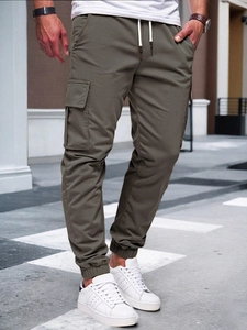 Detail of army green cargo pants featuring large side pockets and drawstring waist