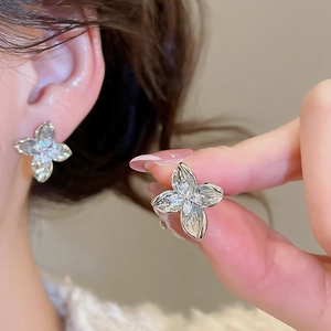 Macro shot of silver clover earrings with sparkling cubic zirconia on a model's ear