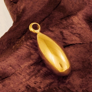 Macro shot of a polished gold teardrop pendant on a rustic natural wood surface