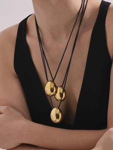 Polished gold tear-drop pendant necklaces with black cord worn by fashion model