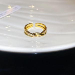 Detail of gold-plated crossover ring with sparkling crystals and black enamel accents