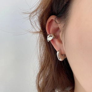 Close-up of minimalist silver ear cuff and hoop earring set with polished mirror finish