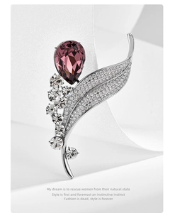 Macro detail of leaf-shaped brooch with purple crystal teardrop and silver stone setting