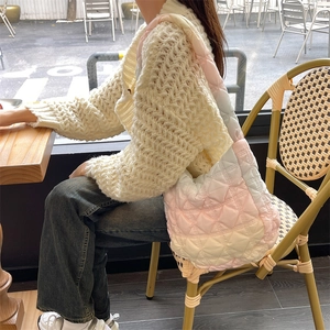 Close-up of pink gradient quilted nylon cloud bag with soft pleats in a cafe setting