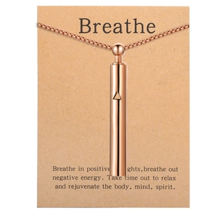 Close-up of rose gold mindfulness breathing whistle pendant on a Breathe gift card