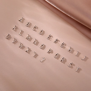 A-Z stainless steel alphabet charms set for DIY jewelry making on pink silk background