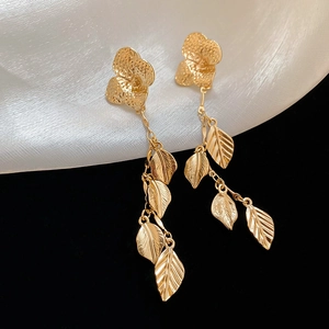 Detail of gold leaf fringe earrings with flower petals on black and white silk background