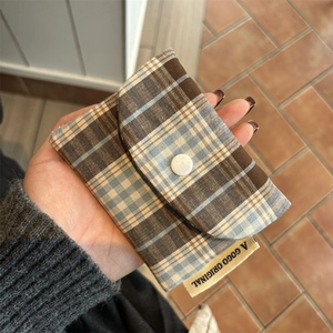 Close-up of brown and blue plaid canvas coin purse with white button held in hand