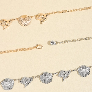Detail of gold and silver body chains with starfish, seashell charms and lobster clasp