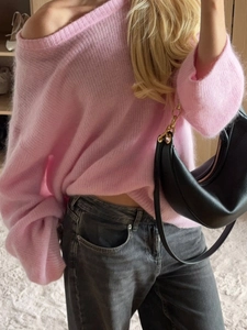 Close-up of pink off-shoulder knitted sweater styled with dark grey jeans and handbag