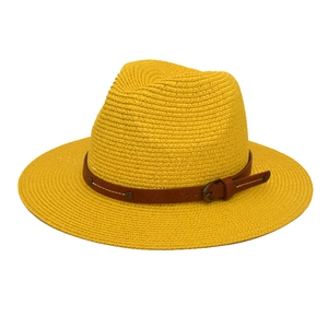 Close-up of yellow straw fedora hat featuring a brown leather belt with metal buckle