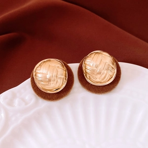 Macro detail of round vintage stud earrings with flocking texture on a ceramic plate