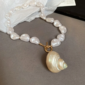 Detail of baroque pearl necklace with a natural conch pendant and golden OT clasp closure