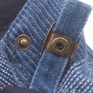 Detail of blue denim fabric with white stitching and vintage bronze adjustable buckle
