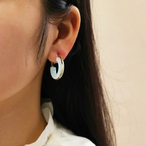 Close-up of model wearing C-shaped gold-plated square earrings with blue resin inlay