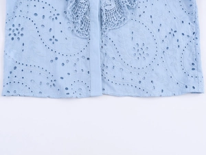 Dettaglio della camicia azzurra con ricami intricati e finiture in pizzo traforato