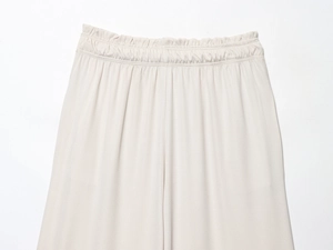 Detailed close-up of beige trousers showing the elastic high waist design and fabric texture