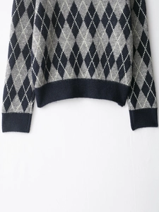 Detailed close-up of argyle knit pattern and navy ribbed hem on a casual sweater