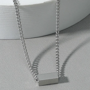Macro view of polished silver cube pendant on sleek curb chain necklace