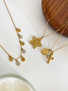 Close-up of gold-plated necklaces with star, cross, and Virgin Mary pendants on wood