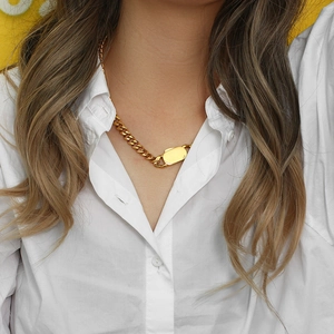 Close-up of golden chunky curb chain necklace with rectangle metal clasp on model