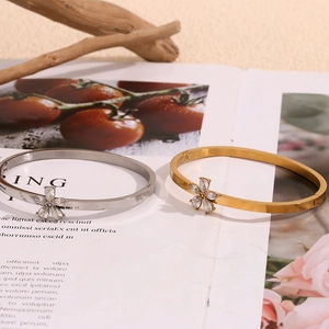 Elegant 18K gold and silver flower bracelets with white zircon petals on a magazine background