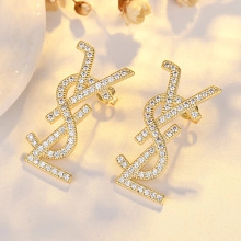 Macro shot of gold tone letter earrings with sparkling white crystals and micro pave detail