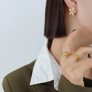 Exaggerated golden floral earrings and minimalist openwork ring on elegant female model