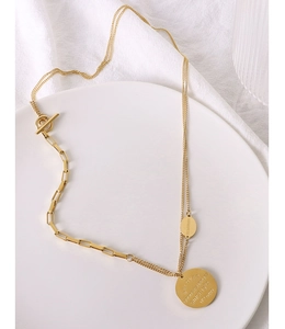 Detailed macro view of gold-plated double-layer necklace with OT clasp and engraved round tag